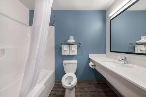 a bathroom with a toilet and a sink and a mirror at WoodSpring Suites Concord-Charlotte Speedway in Concord