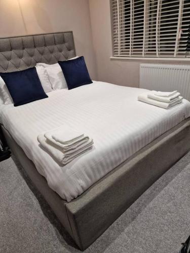 a large bed with white sheets and blue pillows at Beautiful and modern House in Gravesend in Gravesend