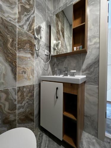 a bathroom with a white sink and a marble wall at KRich Hotel Aktobe in Aktobe