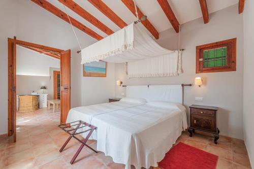 Un dormitorio con una gran cama blanca y una silla. en Els Marsals, en Llucmajor