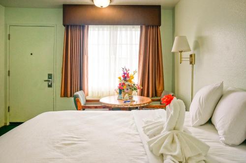 a hotel room with a bed and a table with flowers on it at OceanView Motel in Huntington Beach