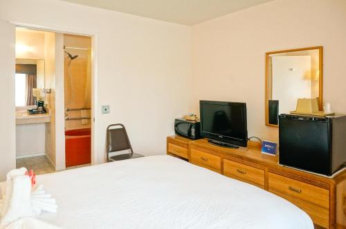 a bedroom with a bed and a television on a dresser at OceanView Motel in Huntington Beach