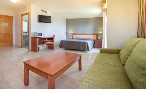 ビナロスにあるEstudios RH Vinarosのベッド、ソファ、テーブルが備わるホテルルームです。