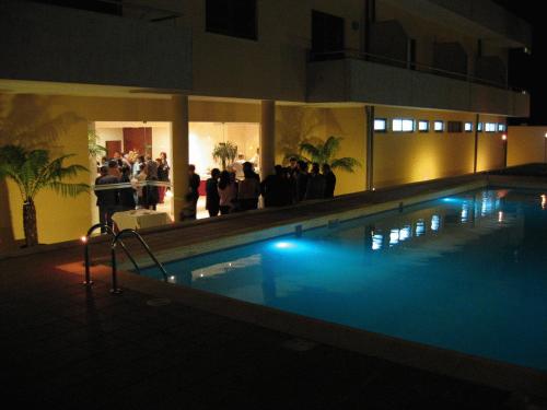 a large swimming pool at night with a crowd of people at Hotel La Fontaine in Esmoriz