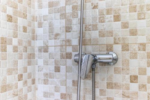 a shower in a bathroom with brown and white tiles at Antigua casa de escritor junto a la playa in Mundaka