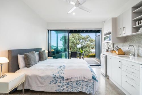 a bedroom with a large bed and a kitchen at Bayview Corner Suite Unit 2 - Paihia Unit in Paihia