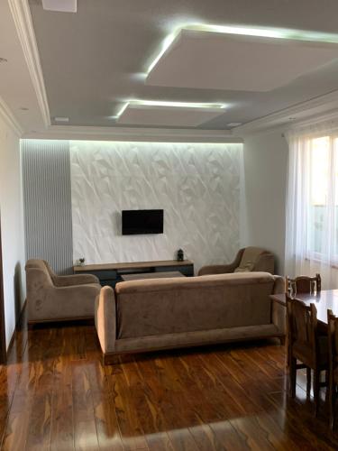 uma sala de estar com um sofá e uma televisão na parede em The SEVAN LAKE HOUSE em Shorzha