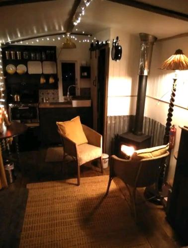 a living room with a stove and a table and chairs at Treguth Glamping Unique Experience - Themed Huts in Saint Day