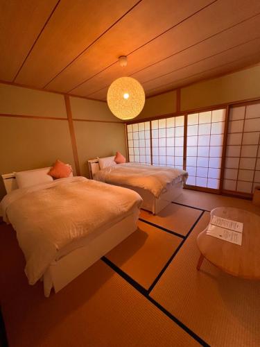 a bedroom with two beds and a chandelier at Yufuin Hoshinosato in Yufuin