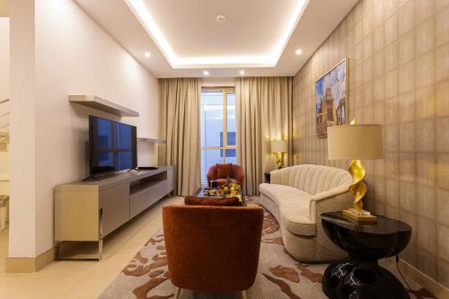 uma sala de estar com uma televisão, um sofá e uma cadeira em Sarwat Park Hotel Riyadh - Diplomatic Quarter em Riyadh
