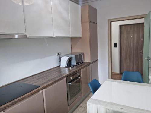 a kitchen with white cabinets and a table and blue chairs at Sasu Apartment in Timişoara