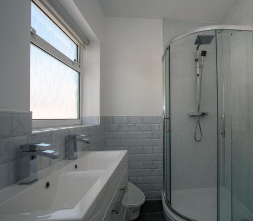a white bathroom with a sink and a shower at Botany Bay Holiday House - Family friendly, 50M from the beach in Kent