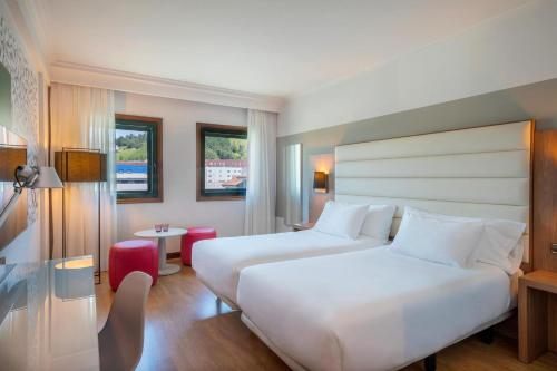 a hotel room with two beds and a table at Hotel Santiago Plaza Affiliated by Meliá in Santiago de Compostela