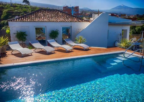 einen Pool mit Stühlen und ein Haus in der Unterkunft Casa Viña: a spectacular away from it all holiday in La Orotava