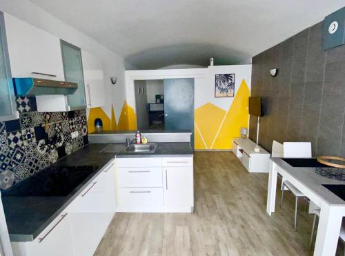 Location T1 Bis (RdC) / Emplacement Ideal في لو بوزين: مطبخ به دواليب بيضاء وجدران صفراء ورمادية