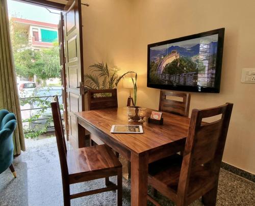 a wooden dining room table with a television on the wall at Peaceful Home2 Stay by Six Lane in Sohāna
