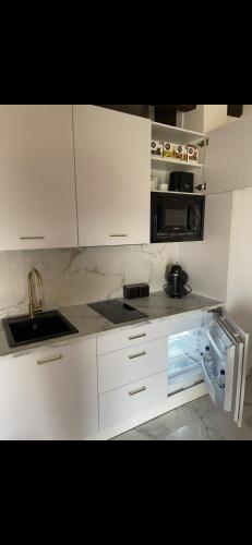 a white kitchen with a sink and a microwave at El Comercio in Villarejo del Valle