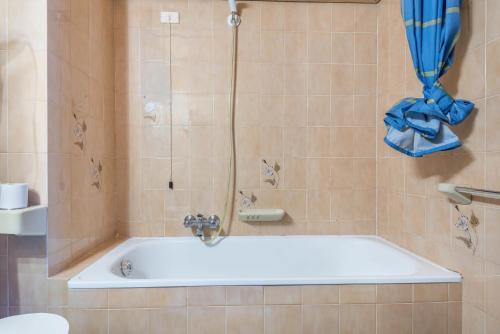 a bathroom with a bath tub with a blue shower curtain at Pension Sonia App 102 in Funes