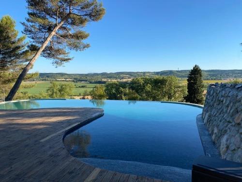 une piscine avec un mur en pierre et un arbre dans l'établissement Domaine de ferrabouc, à Mas-Saintes-Puelles