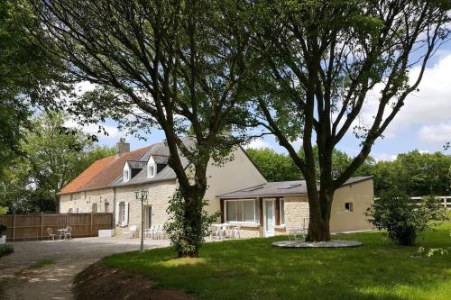 une maison avec deux arbres dans la cour dans l'établissement La Bocagère d' Henri, à Saint-Côme-du-Mont