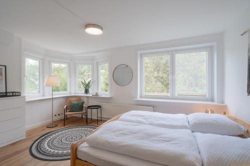a white bedroom with a large bed and windows at Villa Hoheneck in Wildemann