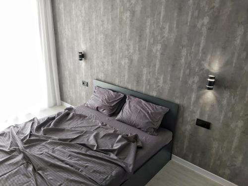 a bed in a bedroom with a gray wall at Люкс Апартаменты Gray Pearl на Подолье in Vinnytsya