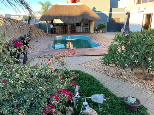 a backyard with a swimming pool and a thatched building at Almina villa in Windhoek