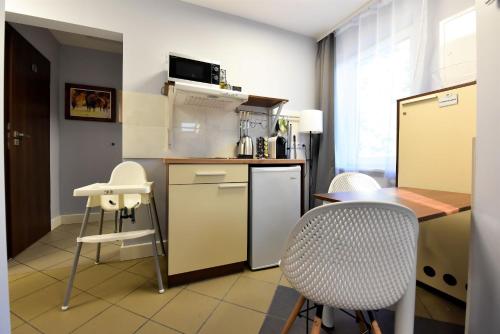 a kitchen with a counter and two chairs and a table at Pensjonat Zuzanna in Hajnówka