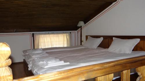 a large bed with white sheets and pillows on it at Недкова къща in Koprivshtitsa