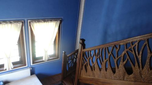 a blue room with a staircase and two windows at Недкова къща in Koprivshtitsa