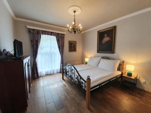 Schlafzimmer mit einem Bett und einem Kronleuchter in der Unterkunft Lesní Hotel Peršlák in Nová Bystřice