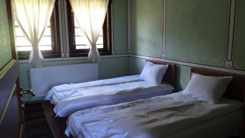 two beds in a room with two windows at Недкова къща in Koprivshtitsa