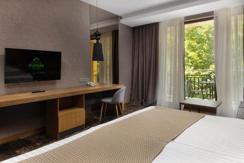 a bedroom with a bed and a desk with a television at Pirin Park Hotel in Sandanski