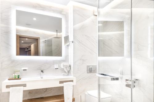 a white bathroom with a sink and a mirror at Pirin Park Hotel in Sandanski