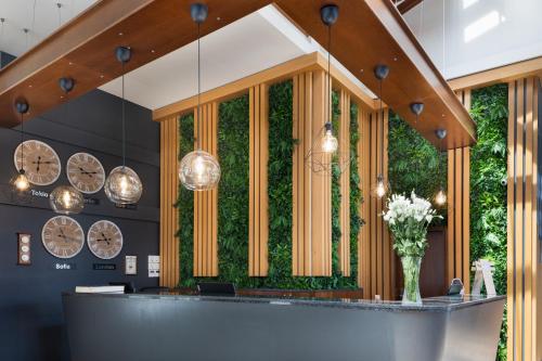 a lobby with a green wall with clocks at Pirin Park Hotel in Sandanski