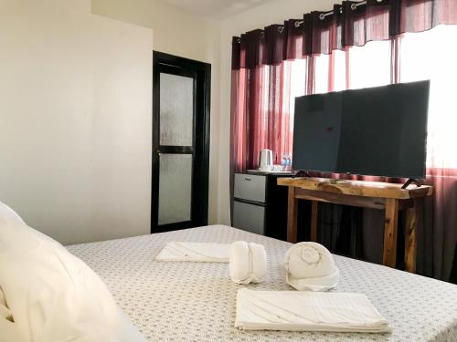 a bedroom with a bed with towels and a flat screen tv at E.I. SUITES in Siquijor