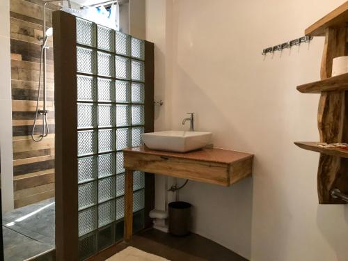 La salle de bains est pourvue d'un lavabo et d'une porte de douche en verre. dans l'établissement E.I. SUITES, à Siquijor