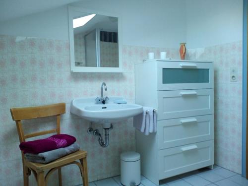 a bathroom with a sink and a mirror and a chair at Haus Huber in Übersee
