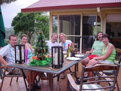 a group of people sitting at a table with a christmas tree at Tropical Coast Retreat - Pet Friendly - Adult only in Kingscliff
