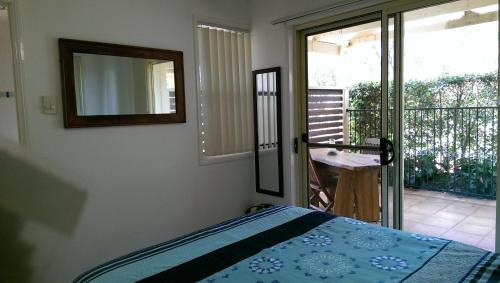 a bedroom with a bed and a mirror and a balcony at Tropical Coast Retreat - Pet Friendly - Adult only in Kingscliff