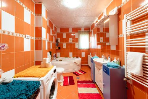 a bathroom with orange and white tile walls and a washing machine at Casa VLC Punct Gastronomic Local Bilbor in Rocoteaş