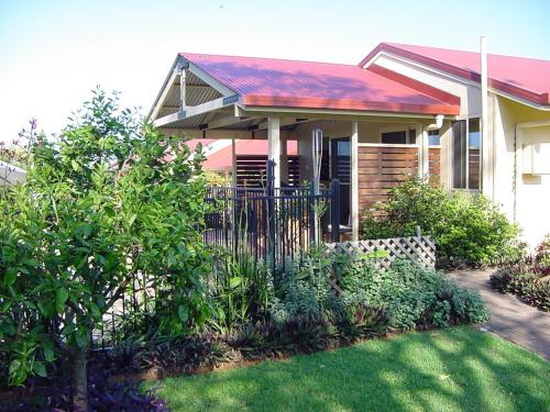 a house with a fence in front of a yard at Tropical Coast Retreat - Pet Friendly - Adult only in Kingscliff