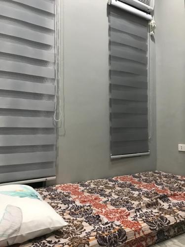 a bed with a quilt on it next to a window at 2-Storey Rental Unit w/ Garage in Balanga Bataan in Tinajero