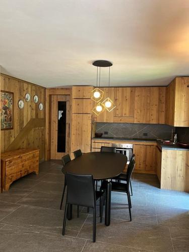 a dining room with a table and chairs and a kitchen at Remina Dolomiti house in Tonadico