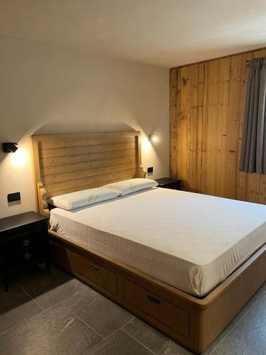 a bedroom with a large bed with a wooden headboard at Remina Dolomiti house in Tonadico