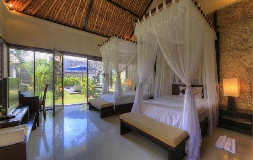 een slaapkamer met 2 bedden en een televisie in een kamer bij Bali Rich Villas in Seminyak