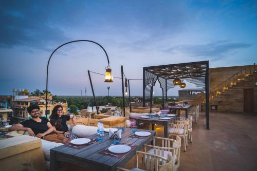 two people sitting on a rooftop patio with tables and chairs at Hotel Grand Khalifa in Jaisalmer