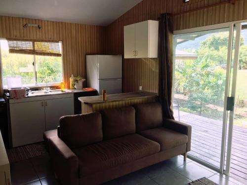 a living room with a couch and a kitchen at Fare To'erau & Mara'amu in Papetoai