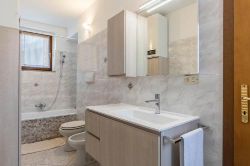 uma casa de banho com um lavatório, um WC e um espelho. em La Coccola di Giovanni em Levico Terme