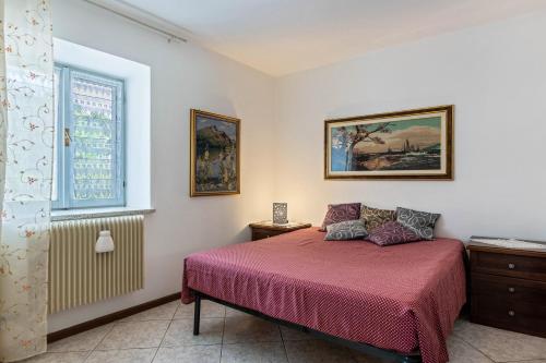 a bedroom with a bed with a red bedspread and a window at La Coccola di Giovanni in Levico Terme